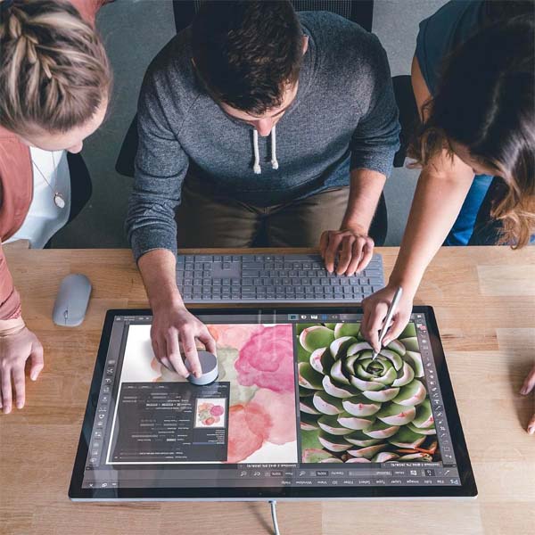 Team collaborating around a Surface Studio