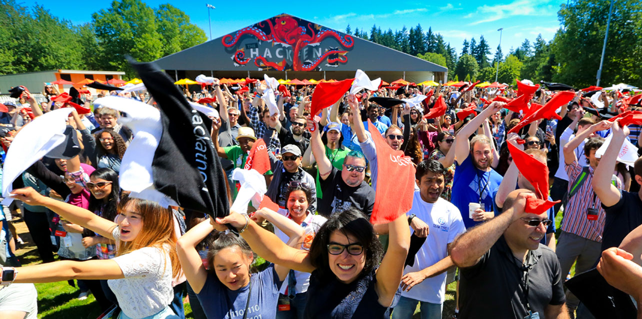 A group of happy people waving banners at an outdoor Hackathon event