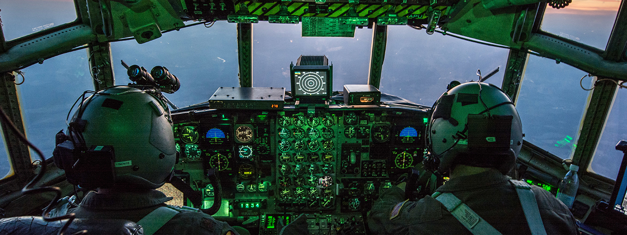 2 air force pilots in the cockpit of an aircraft flying at dusk