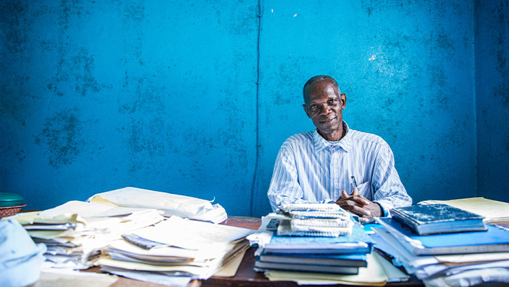 Real people. Male social worker sitting at desk in his office at a psychiatric hospital in Liberia, looking directly at camera.