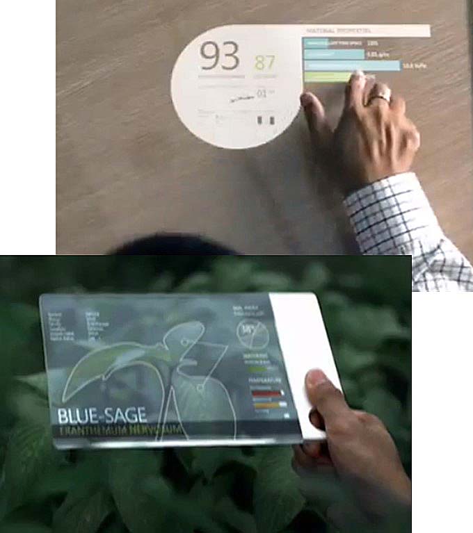 A flat, transparent display laid on a desk and another held in a hand