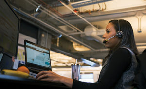 Image of a firstline worker working at her desk, answering a call on her headset.