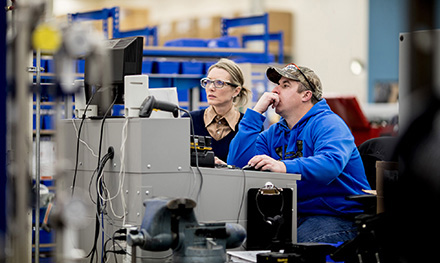 Image of two firstline workers looking at a computer monitor.