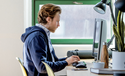 Image of a worker sitting at his desk, hands hovering over his keyboard.