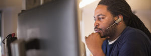 Image of a firstline worker looking at several computer monitors.