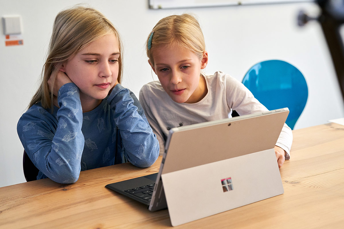 Zwei Mädchen sitzen vor einem Computer und programmieren