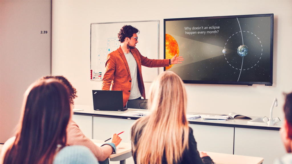 Ein Lehrer zeigt seinen Schülern die Lerninhalte digital an einem Bildschirm.