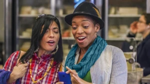 Zwei Frauen schauen erfreut auf ihr Smartphone.