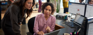 Image of two tech workers collaborating over a laptop.