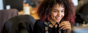 Image of a worker smiling at her computer.