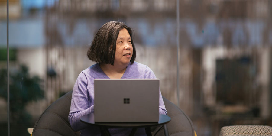 A woman who is visually impaired works on a laptop at a desk