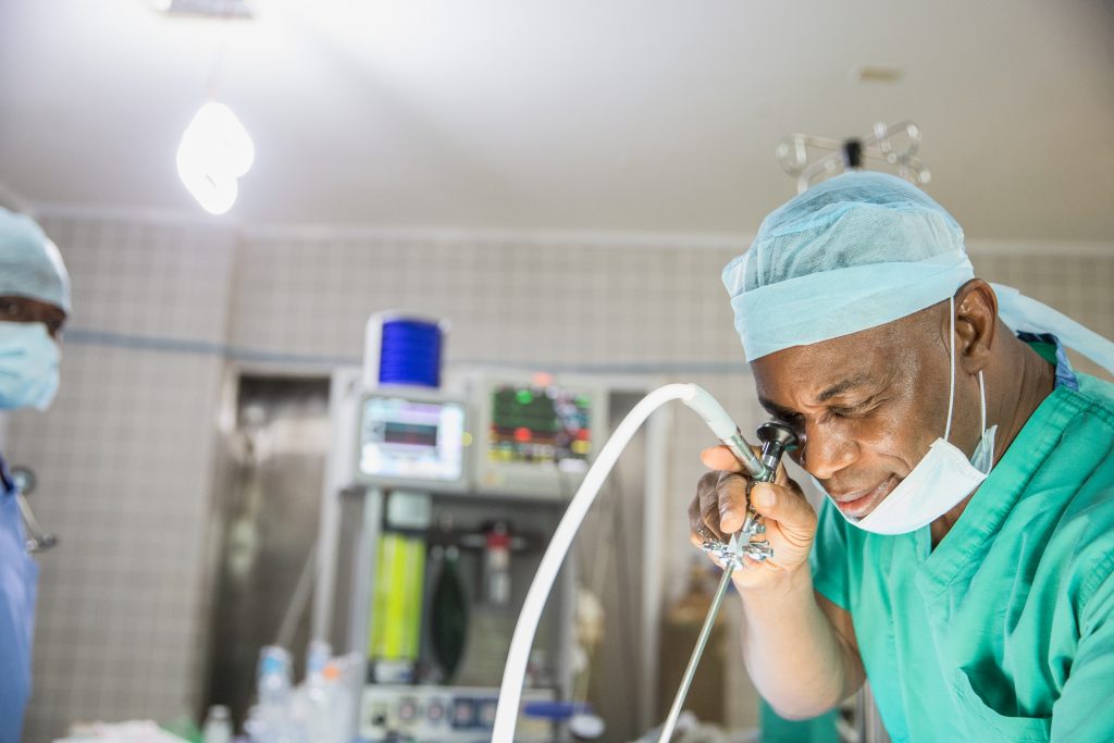 A male doctor peers through a surgical scope in operating room of medical facility