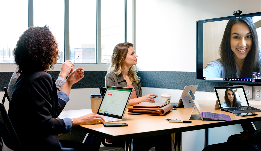 Students meeting in a conference room on a video call with their female team member