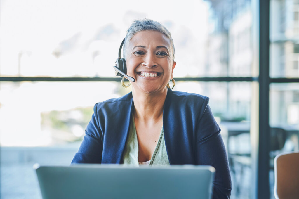 Smiling woman wearing a headset works at laptop