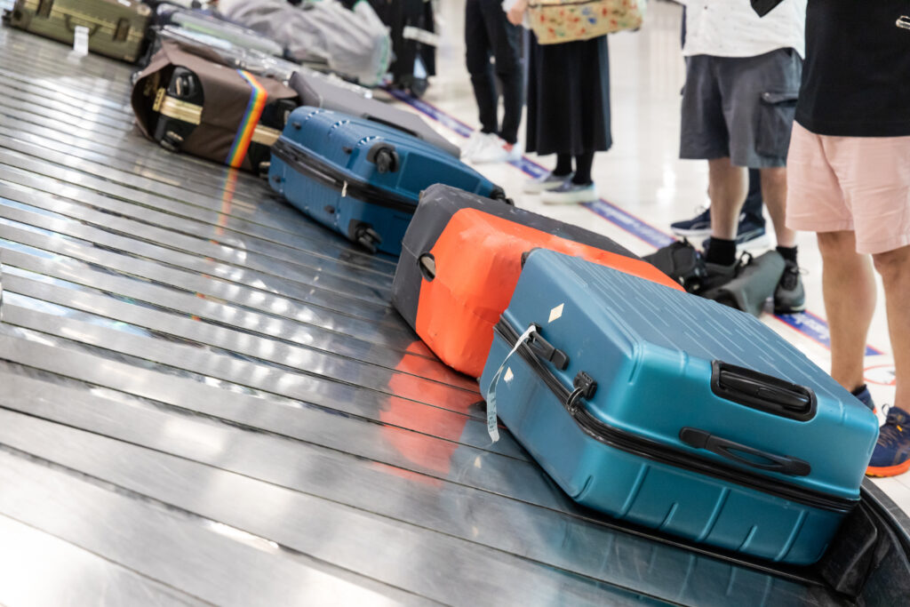 Luggage on carousel at airport with passengers waiting to claim their bags