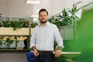 A male office worker smiles at the camera