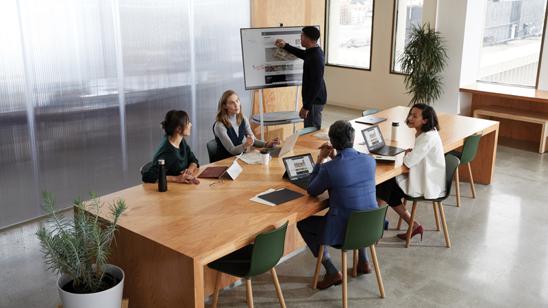 Man presents at a work meeting using a Microsoft Surface Hub 2S