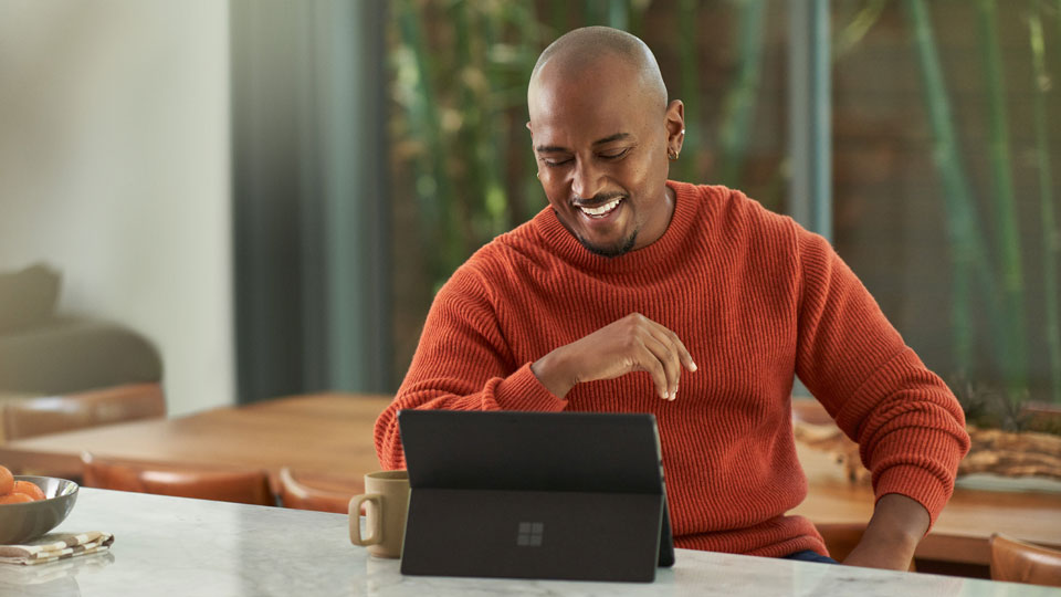 A man laughs during a video-call on a Microsoft Surface Go