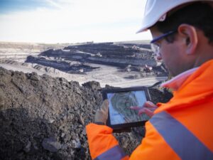 Ecologist using digital tablet surveying surface coal mine site, elevated view
