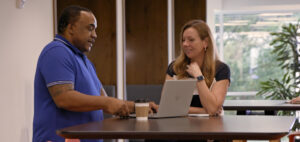 Photo of Delvin Holman and Kerrie Davis, two Lumen Technologies marketing employees, conferring at a table with a computer.