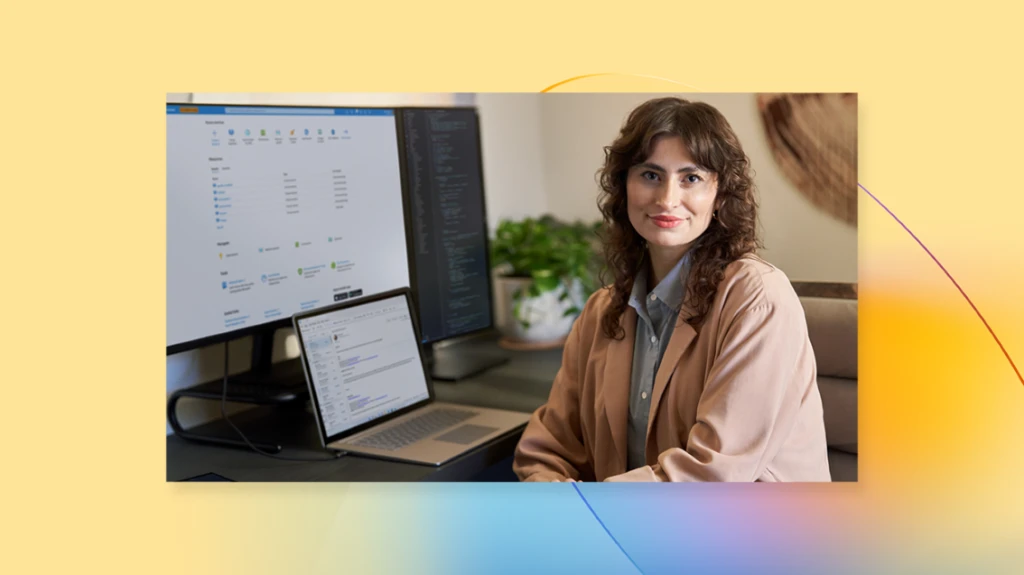 Woman smiling at camera next to computer screen