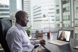 Male business executive working on a Surface Pro Book at desk, running Microsoft Teams.