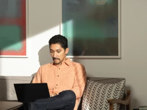 A man sitting on his living room couch working on a Lenovo ThinkPad X1 Carbon. Remote Working collection. Keywords: remote work, remote working, work from home, working at home, home office