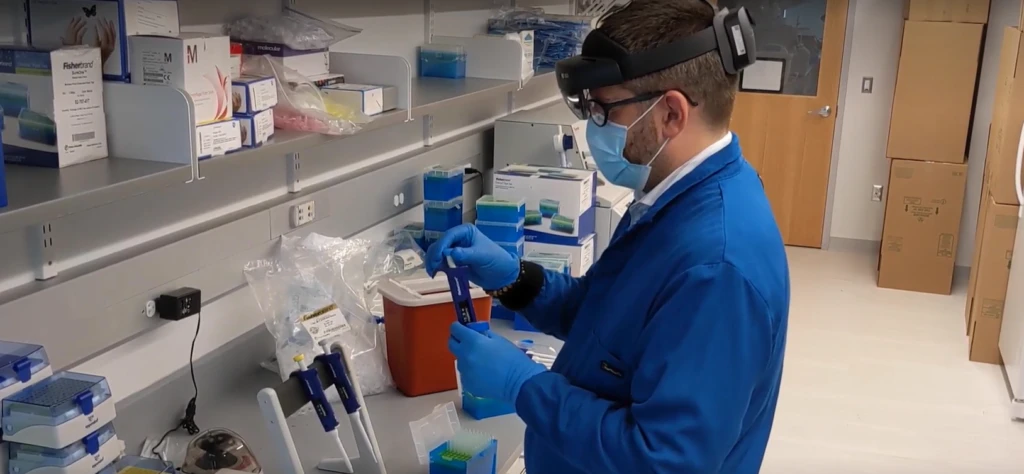 A technician in a laboratory wearing HoloLens and working with lab materials