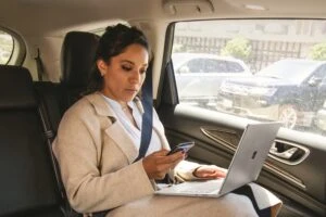 A sales manager in the car with a laptop.