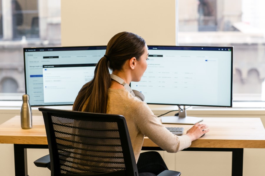 A woman sitting at a desk in front of a multi-screen workstation.