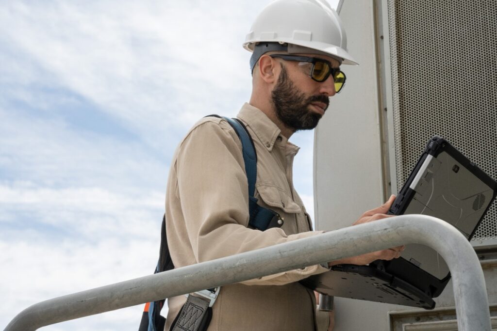 Field engineer viewing data on a laptop after inspecting turbines on a wind farm.