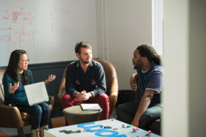 Photo of three colleagues sitting around a table discussing a data maintenance strategy for their organization.