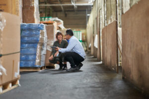 Photo of two people discussing a shipment in a textile warehouse.