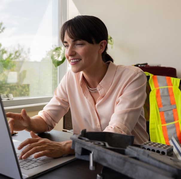 Woman works in an office on a Teams meeting where she interacts with frontline workers using mixed reality in manufacturing.