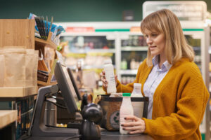 Woman at Self Checkout Buying Dairy Products and Smiling