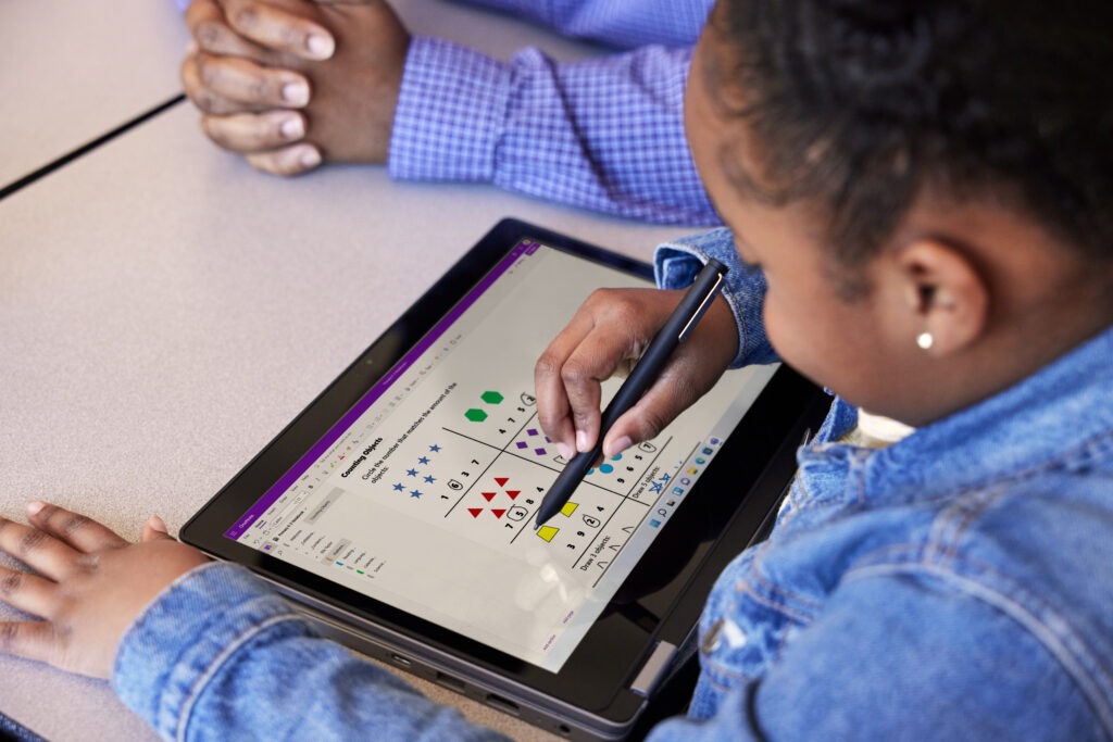 A child working with a teacher on a tablet, engaging in math problems.