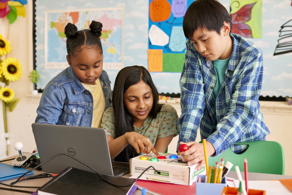 Three elementary school students working together in a classroom setting.