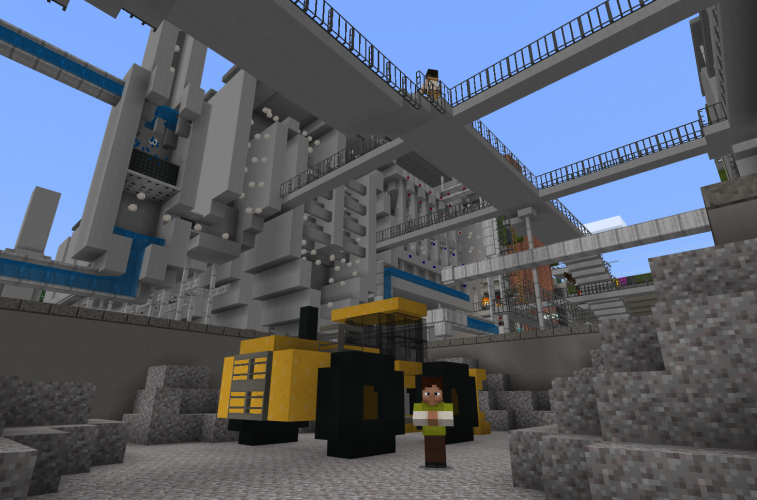 A person stands next to a bulldozer in an industrial complex in Minecraft: Education Edition