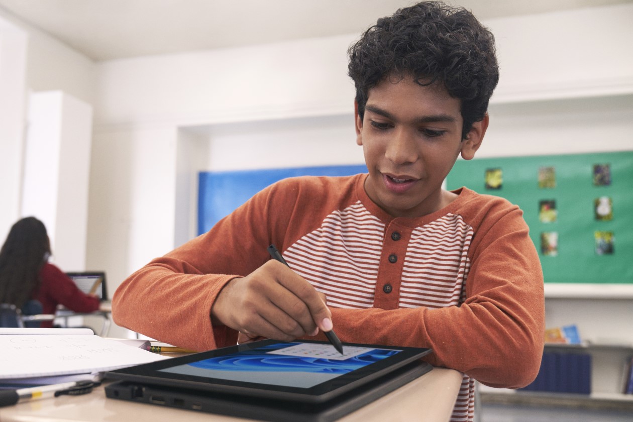 Decorative. A student working on a laptop at a school desk.