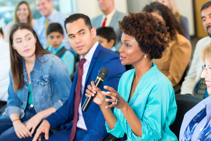 A woman gestures while asking a political candidate a question during a town hall meeting.