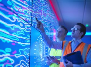 Geologists studying graphical display of oil and gas bearing rock on screens.