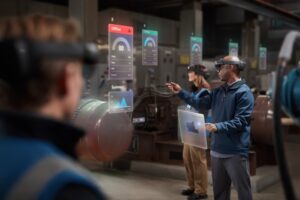 Two men and a woman collaborating using Microsoft Hololens 2 on the manufacturing floor. Contains hologram scenario. Contextual imagery.