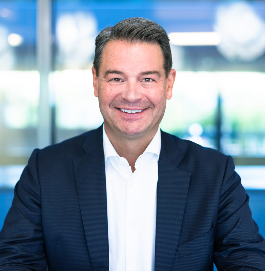 Headshot of Christian Thier -a man wearing a suit and tie smiling at the camera