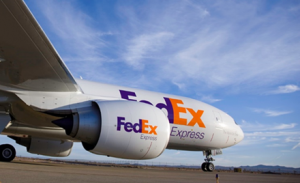 A FedEx plane sits on a runway preparing for takeoff.