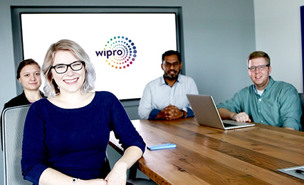 Image of a group of Wipro employees sitting around a conference table.