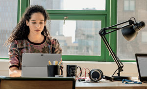 Image of a young small business female with laptop in modern workplace.