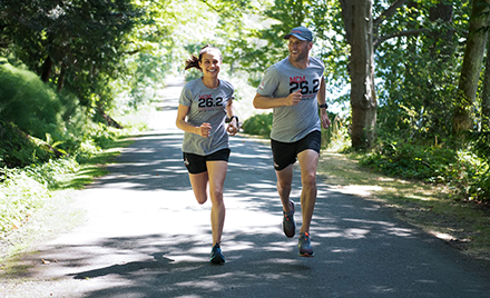 Image of two runners jogging down a forested road.
