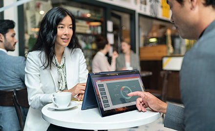 Image of two workers meeting over a table and an HP Elite Dragonfly.