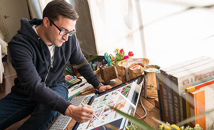 Image of a designer inking with a pen on a large tablet.