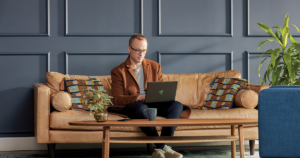 Image of a man working with a laptop PC on a couch.
